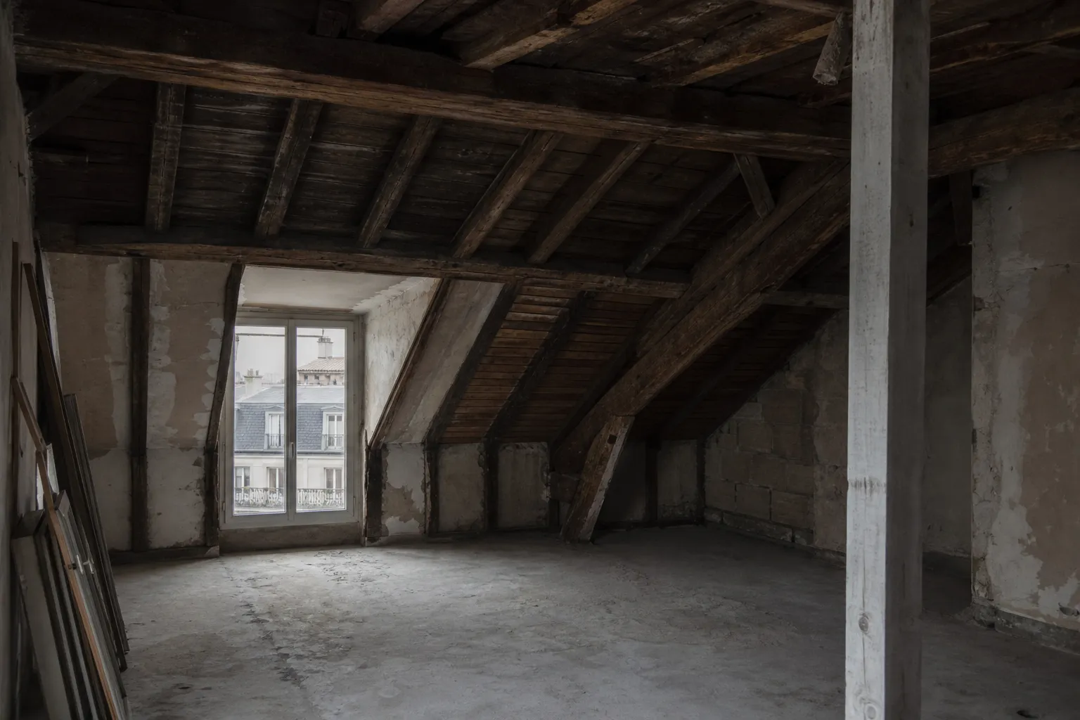 Intérieur d’un comble mansardé parisien vide, brisis raide et terrasson plat se rejoignant à la ligne de bris