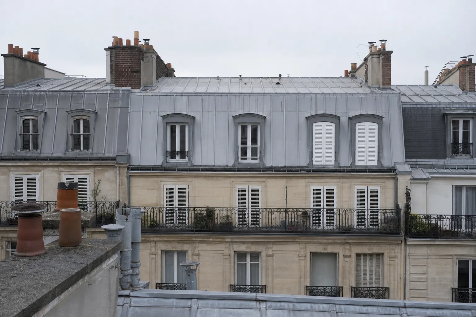 Immeuble haussmannien vu d’un toit voisin, comble en zinc à joints debout réguliers et lucarnes alignées