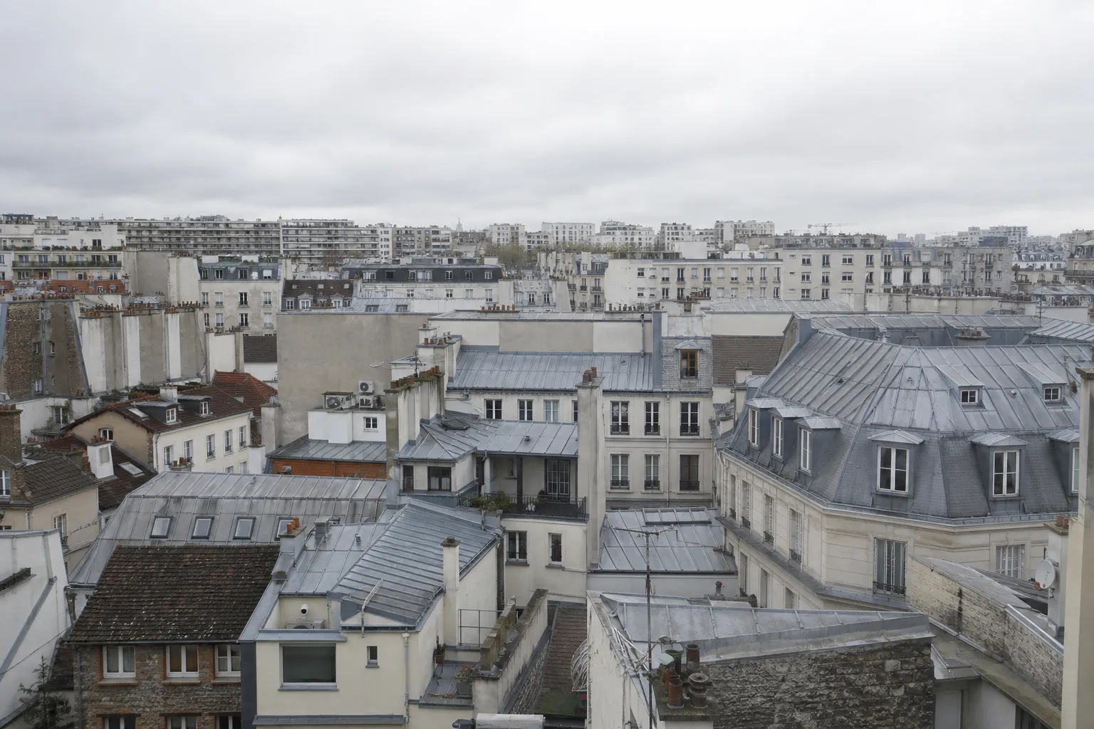 Toits de la première couronne parisienne vus depuis une terrasse, zinc, ardoise et tuile mécanique mêlés