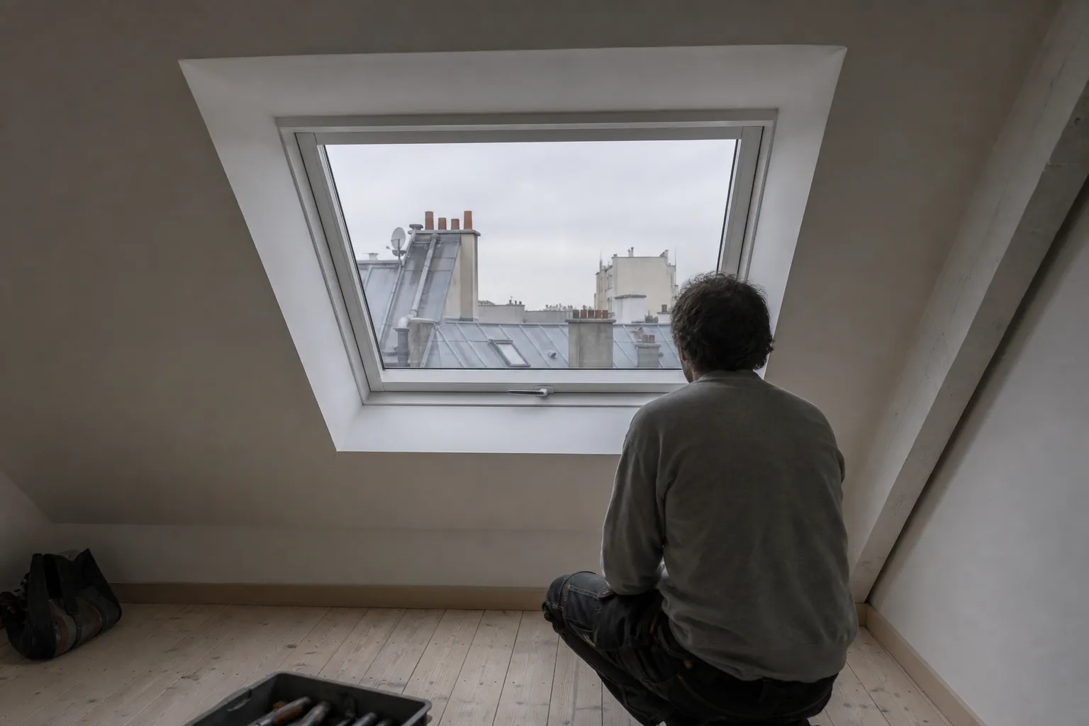 Fenêtre de toit posée vue depuis une pièce de comble terminée, ébrasement plâtré et plancher nu