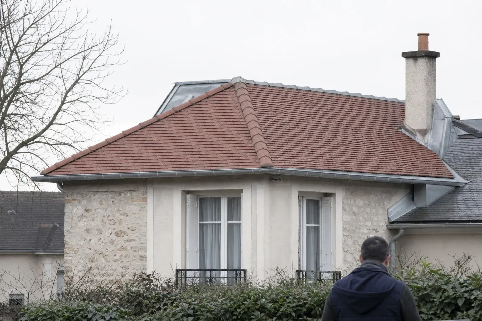 Toit de pavillon de banlieue recouvert de tuiles mécaniques neuves, faîtage et gouttière de zinc
