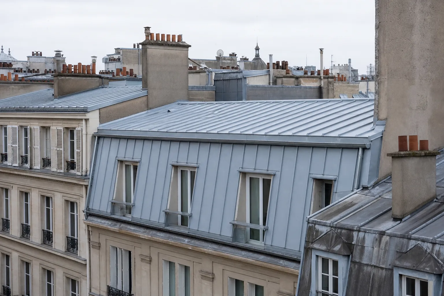 Versant de zinc refait à neuf sur un immeuble parisien, joints debout clairs du faîtage à l’égout